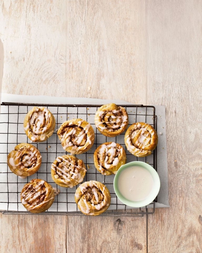 best breakfast recipes, cinnamon buns, with white frosting, on a black metal railing, wooden table