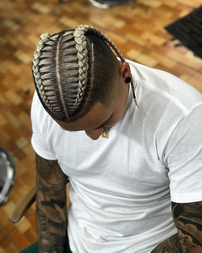 man with black hair, blonde highlights, braided hairstyles, wearing a white t shirt, sleeve tattoos