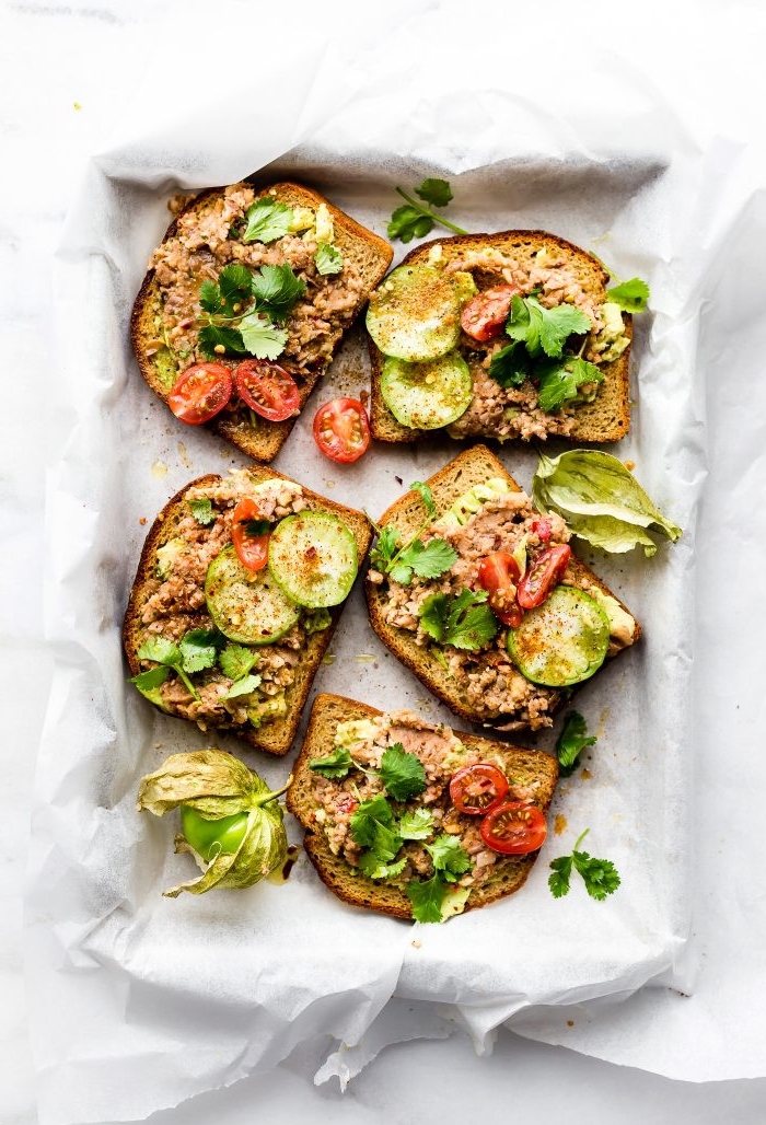 avocado toasts, with different garnish, breakfast recipes, white baking sheet, cherry tomatoes