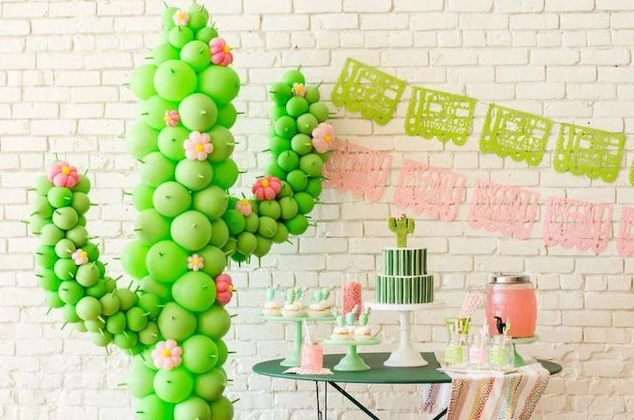 cactus made out of green balloons, green metal table, white brick wall, baby shower decorations, dessert table