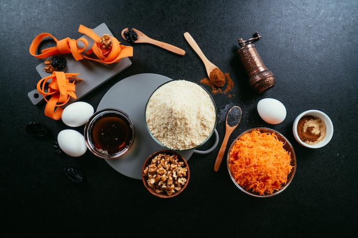 necessary ingredients, all placed in different bowls, carrot cake recipe, arranged on black surface