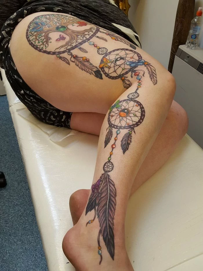 large leg tattoo, whole leg, small dreamcatcher tattoo, woman laying, on a white leather bed