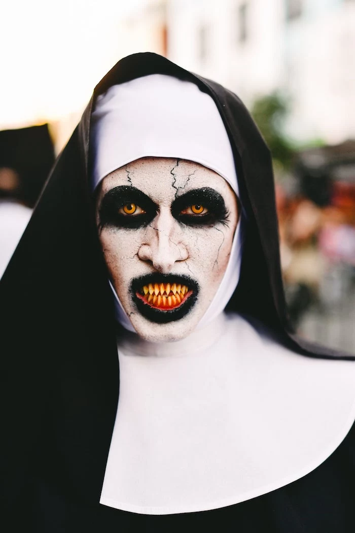 woman dressed as the nun, from the conjuring, halloween costumes, face make up, fake teeth, contact lenses
