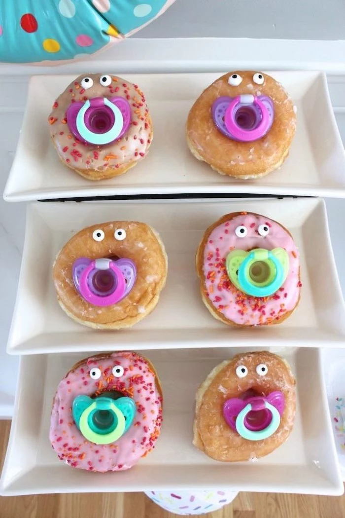 sprinkled donuts, with pacifiers, on white plates, dinosaur baby shower