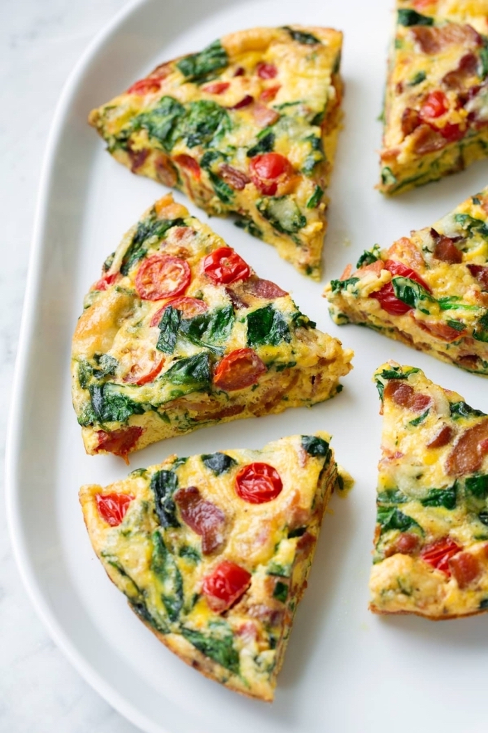 baked casserole, with spinach, cherry tomatoes, white plate, great breakfast ideas, marble countertop