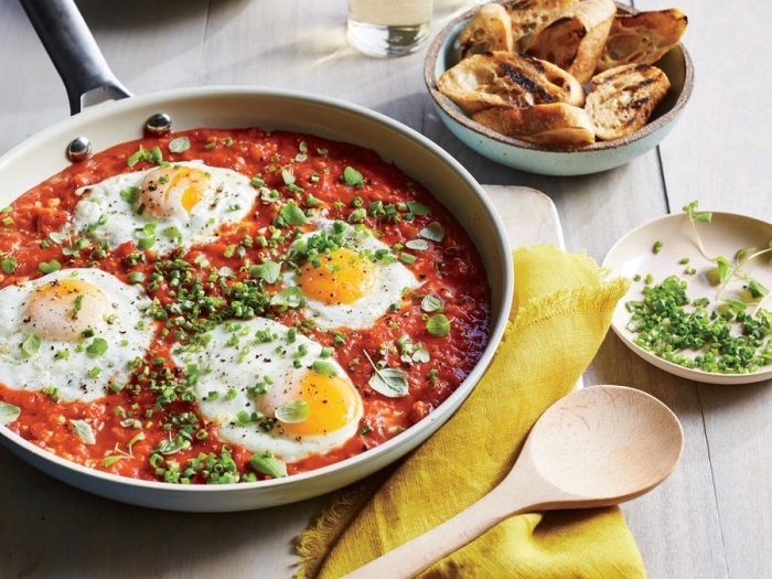 fried eggs, in tomato sauce, chives on top, breakfast brunch, wooden spatula, toasted bruschettas