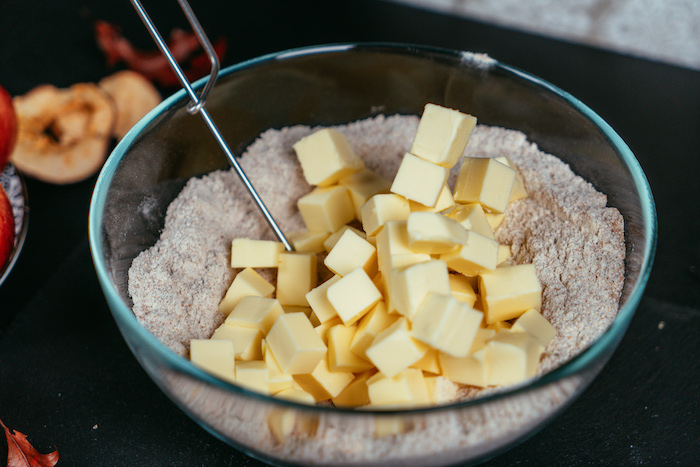 flour and butter mixed together in a glass bowl, placed on black surface, apple pie recipe