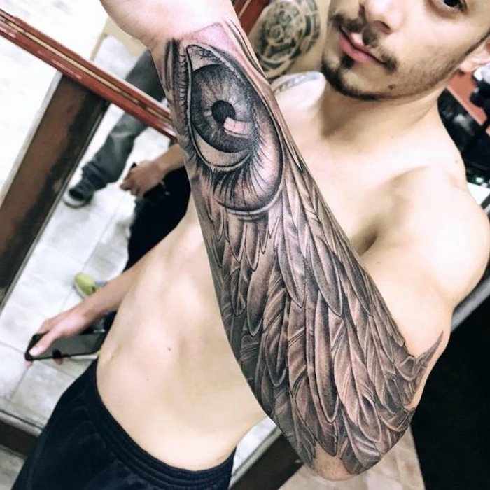 angel wing and eye, forearm sleeve tattoo angel and demon tattoo, man posing for a photo
