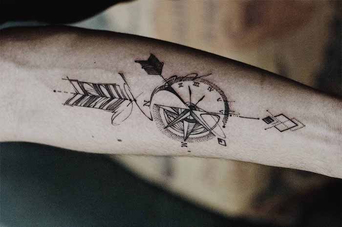 half watch, half compass, large arrow, anchor and compass tattoo, forearm tattoo, blurred background