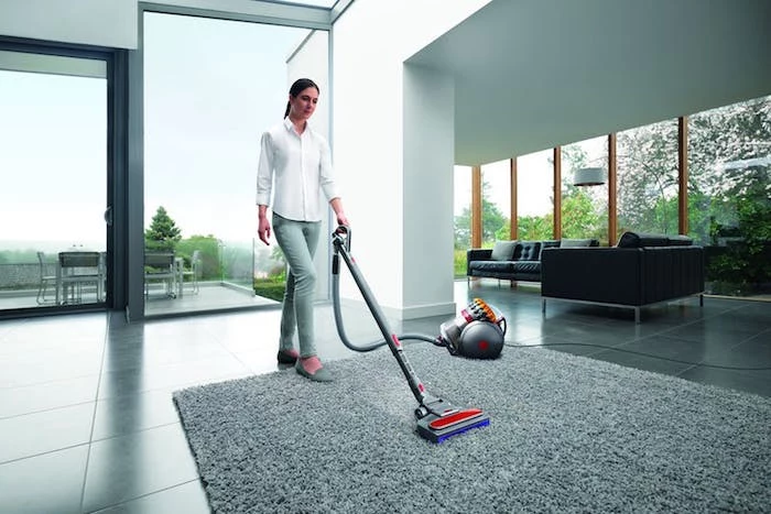 woman cleaning, wearing white shirt, grey trousers, best vacuum cleaner, gray carpet, tiled floor