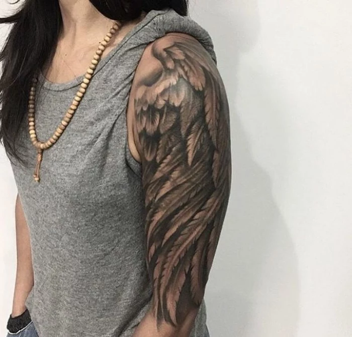 arm sleeve tattoo, angel wing, angel and devil tattoo, woman with black hair, grey top, wooden necklace