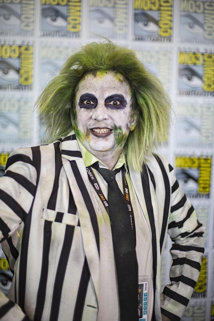 man dressed as beetlejuice, wearing a green wig, black and white, striped blazer, adult halloween costumes