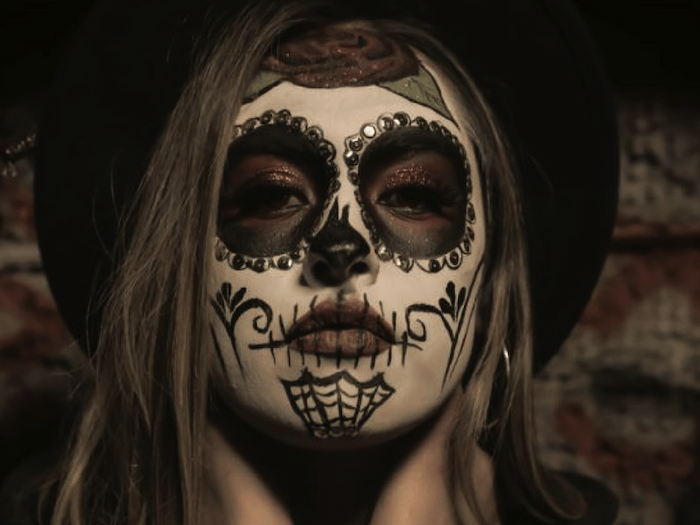 woman with black hat, calavera make up, halloween costume ideas for women, brown hair