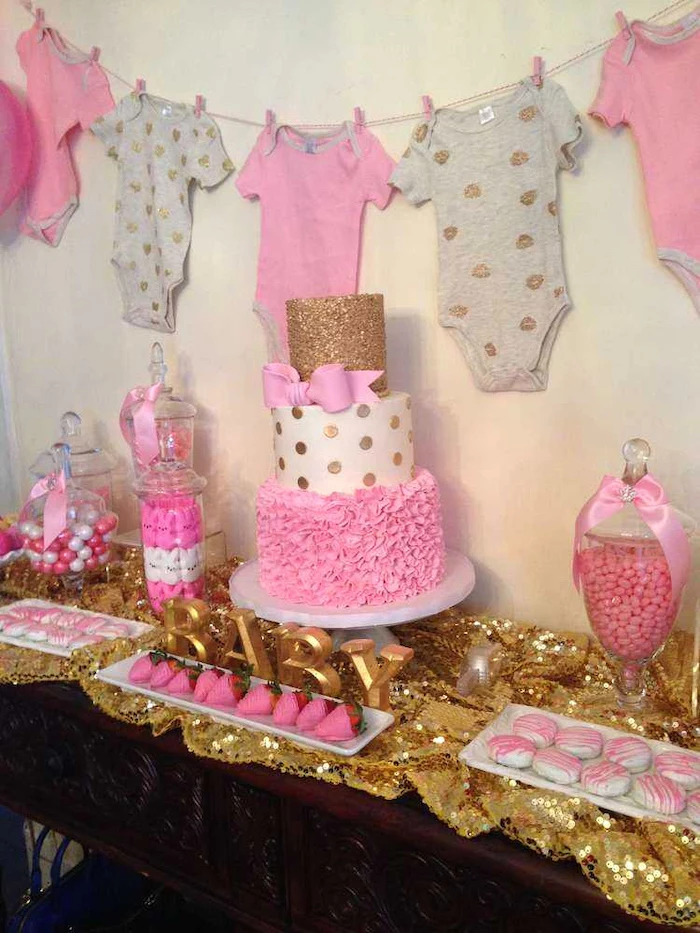 hanging pink and grey onesies, three tier cake, cookies and strawberries, when to have a baby shower, candy jars