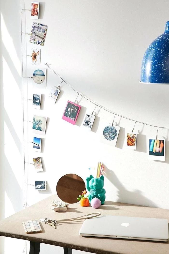 photos hanging on a string, above a wooden desk, cute office decor, keys phone and laptop, white wall