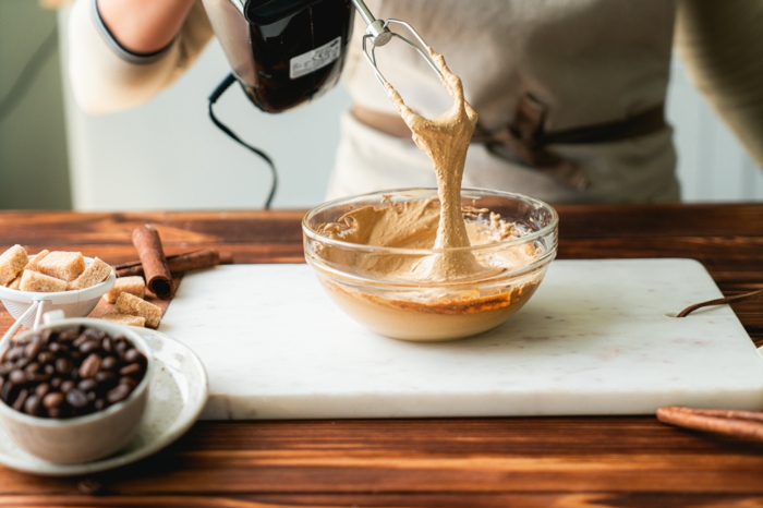 dalgona coffee recipe, instant coffee and sugar, whisked together in glass bowl, placed on wooden surface