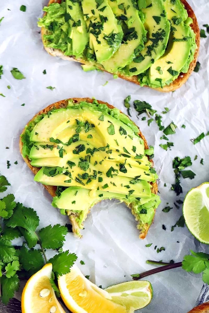 avocado toast, lemon and lime slices, covered in herbs, brunch ideas, white baking sheet