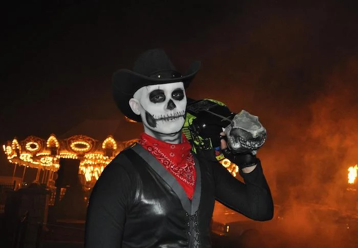 man with a chainsaw, skeleton face makeup, wearing a hat, red bandana, black leather vest, easy halloween costumes