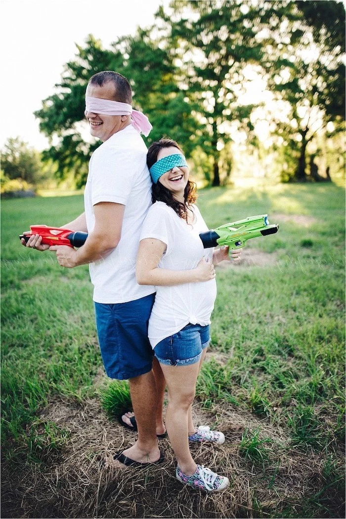 man and woman, standing back to back, gender reveal party, golding nerf guns, wearing blindfolds
