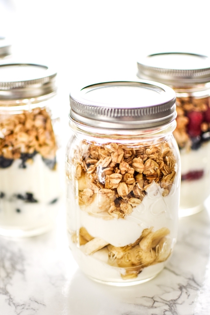 yoghurt and granola, inside a mason jar, brunch potluck ideas, chopped banana, strawberries and blueberries