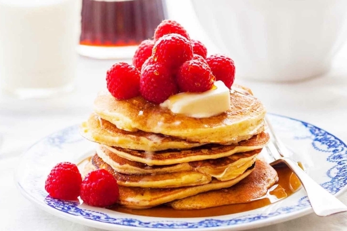 stacks of pancakes, with butter and honey, raspberries on top, breakfast and brunch, white plate