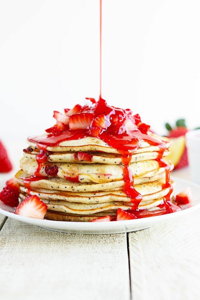 stacks of pancakes, strawberry jam, chopped strawberry, breakfast sides, wooden table