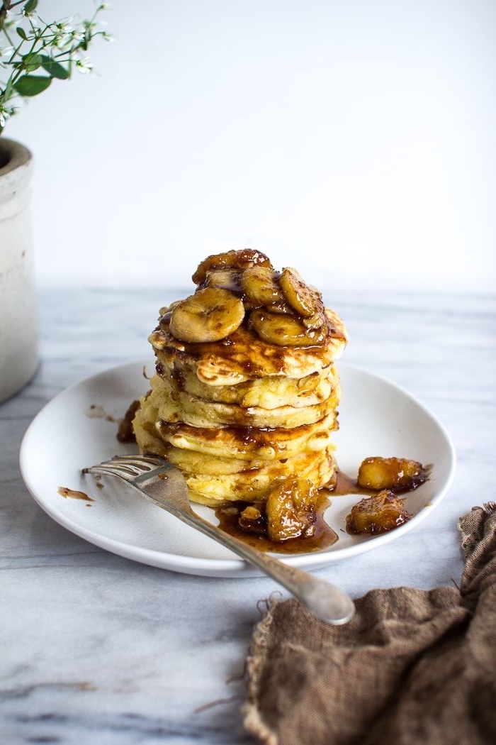 stacks of pancakes, sliced bananas, breakfast sides, white plate, marble countertop