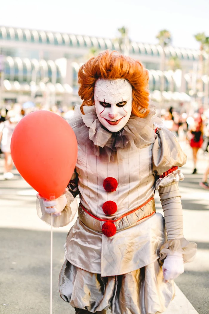man dressed as pennywise, it movie inspired costume, diy halloween costumes, holding a red balloon