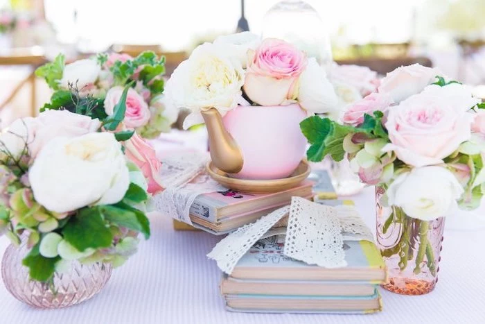 small teapot, flower bouquets inside, on top of books, baby shower table decorations, white ribbons