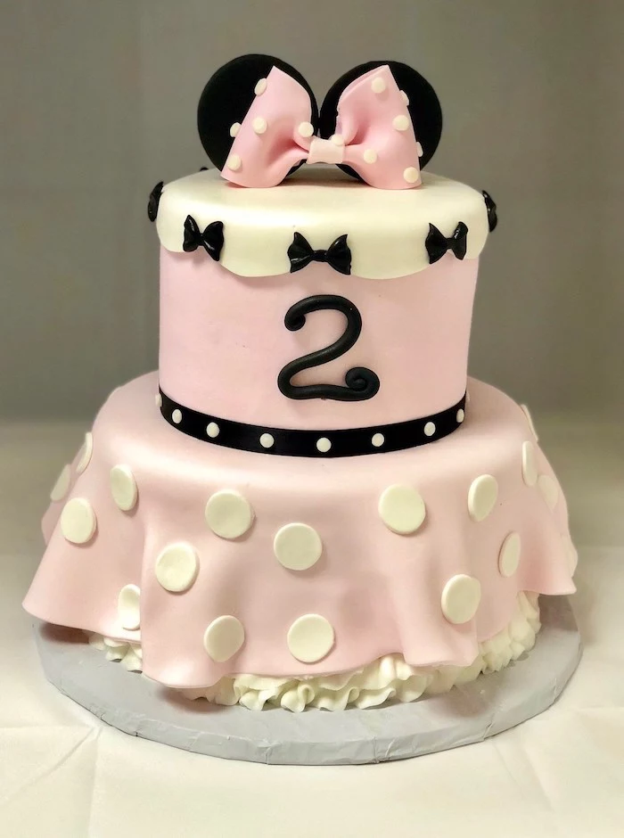 two tier cake, pink and white fondant, white frosting, minnie mouse cake decorations, white background