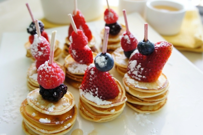 stacks of mini pancakes, brunch ideas for a crowd, raspberries and strawberries, powdered sugar on top