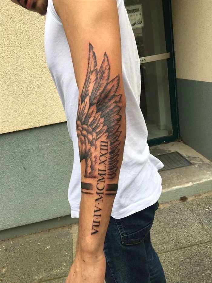 angel wings tattoo on back, roman numerals, arm tattoo, man with white top and jeans, watercolor angel tattoo