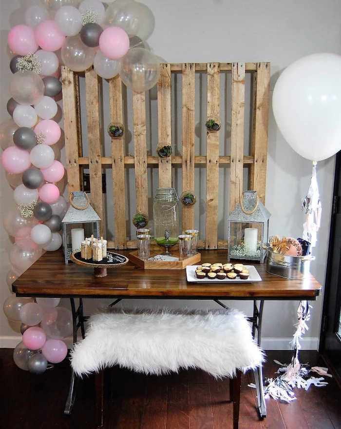 pink white and grey decor, wooden pallet, wooden table, places to have a baby shower, candle lanterns
