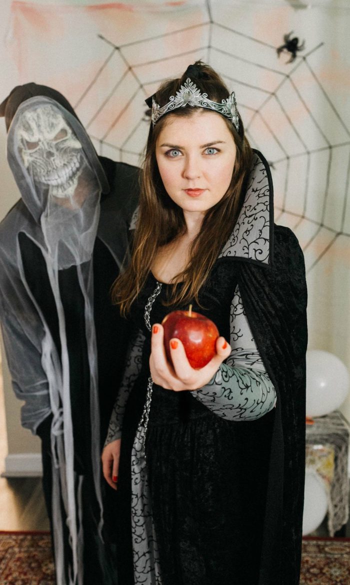 man with a skeleton costume, famous halloween characters, woman dressed as the evil queen, holding a red apple