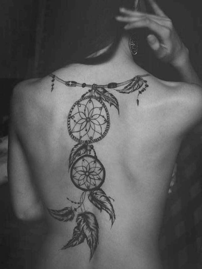black and white photo, dream catcher tattoo on back, woman holding her hair, black hair