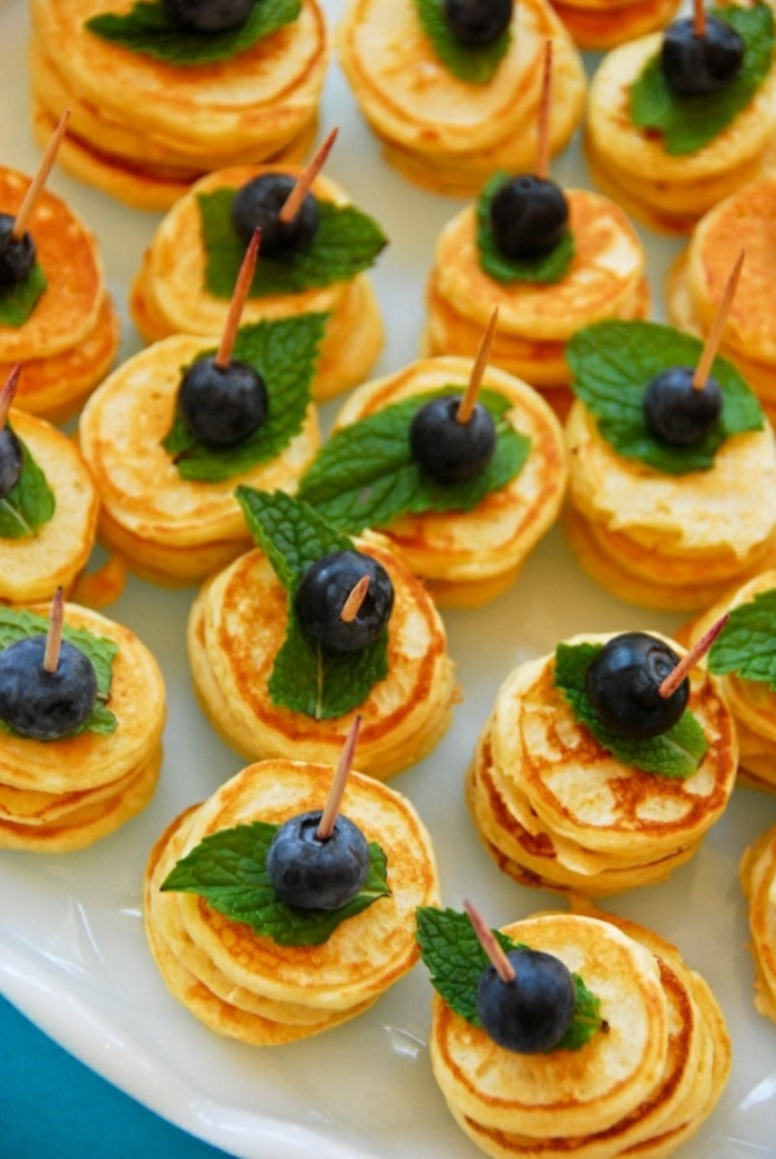 stacks of mini pancakes, fancy breakfast, mint leaves, blueberries on top, white plate