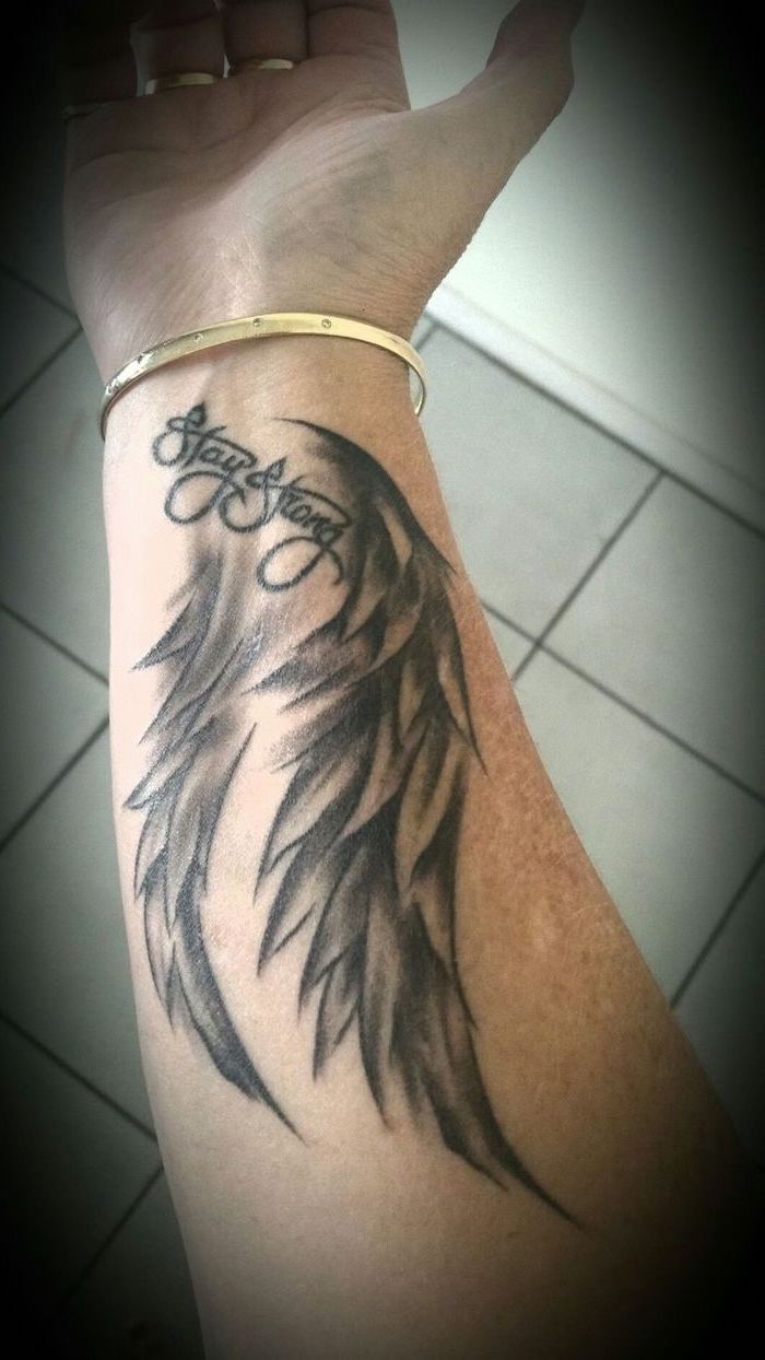 wrist tattoo, stay strong, angel wings, cross with wings tattoo, white tiled floor, gold bracelet
