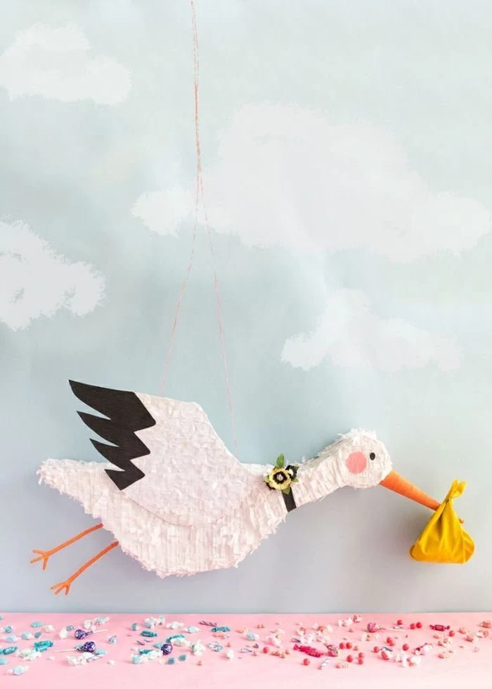 gender reveal ideas for family, pinata in the shape of a stork, candy on the table, blue background