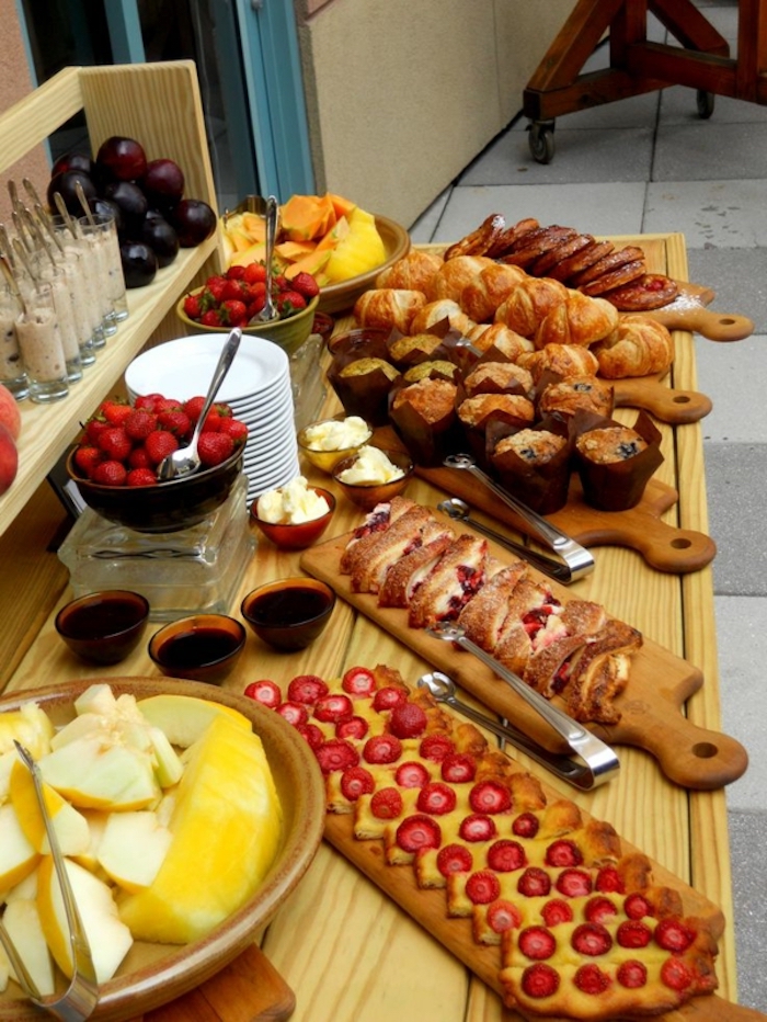 brunch table, fancy breakfast, wooden boards, bowls of different fruits, stack of plates