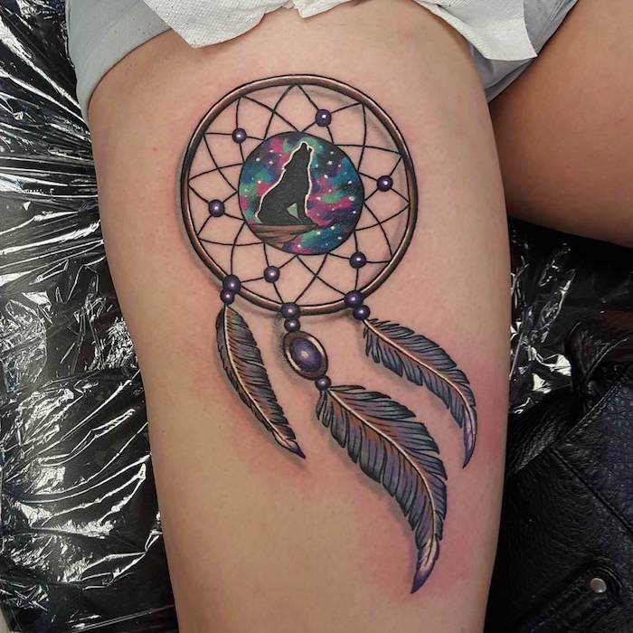 dreamcatcher tattoo meaning, wolf howling, watercolor sky, thigh tattoo, grey shorts