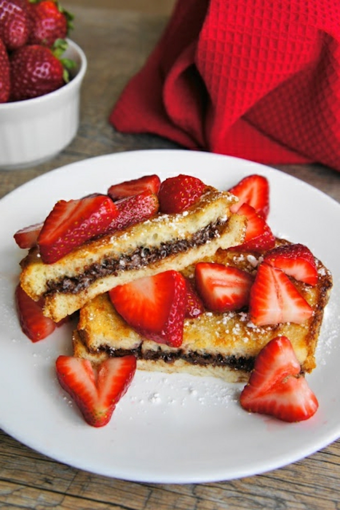 french toast, with nutella, slices of strawberries, things to make for breakfast, white plate, powdered sugar