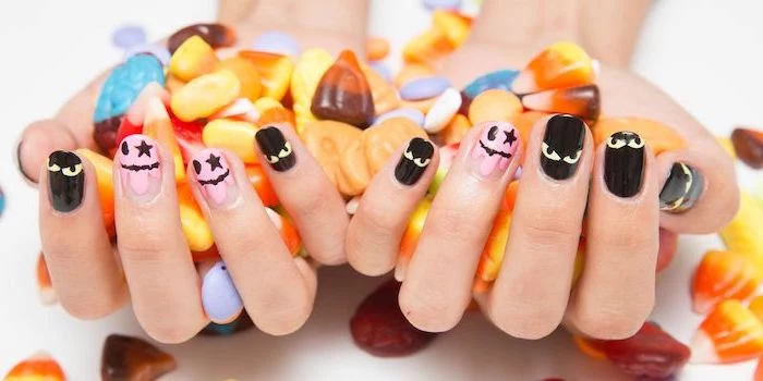 two hands, holding candy, short squoval nails, orange ombre nails, pink and black nail polish