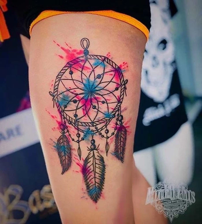 thigh tattoo, watercolor tattoo, small dream catcher, black and yellow shorts, blurred background