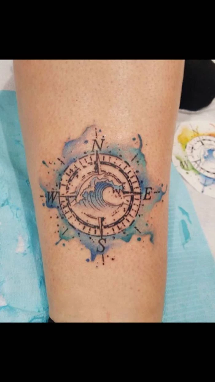large wave, watercolor tattoo, blue color, compass tattoo forearm, leg tattoo, blue sheet of paper