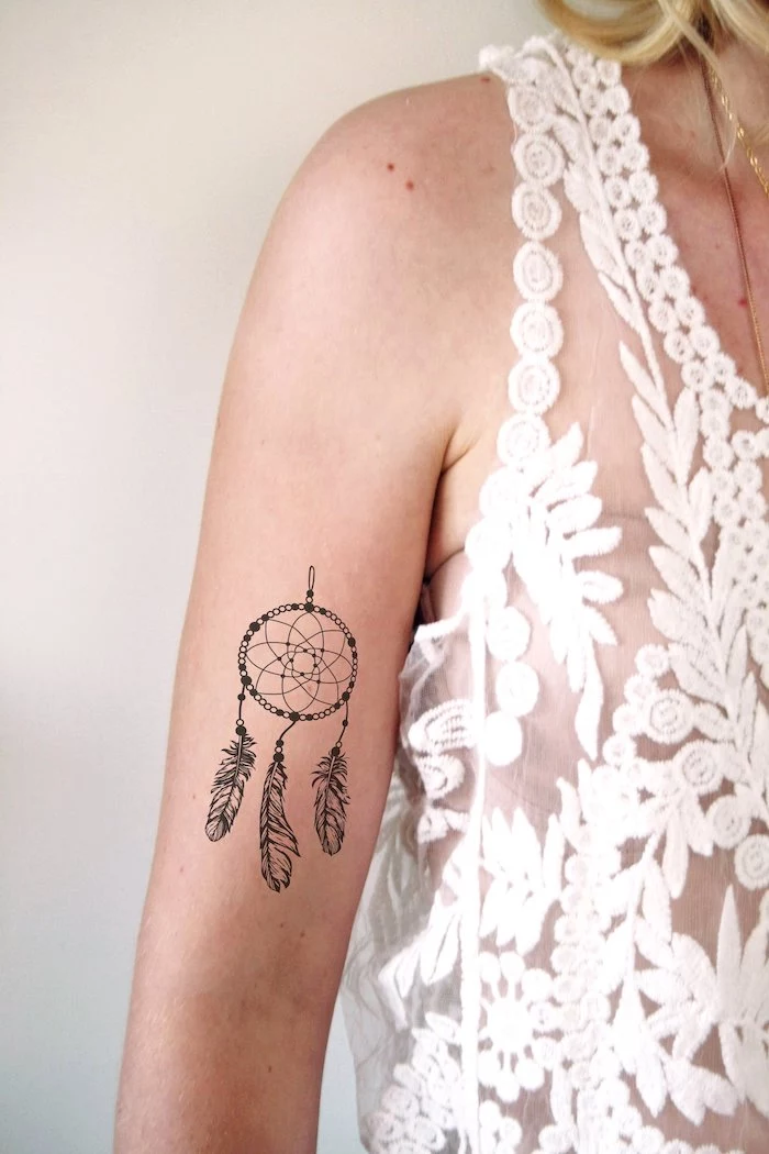woman wearing a white top, dream catcher tattoo ideas, inside arm tattoo, white background