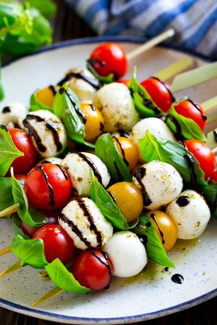 cherry tomatoes, basil and mozzarella, on wooden skewers, breakfast finger foods, white plate