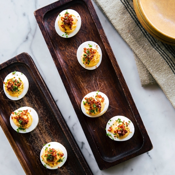 breakfast recipe ideas, wooden plates, eggs filled with mayo, chives on top, marble countertop