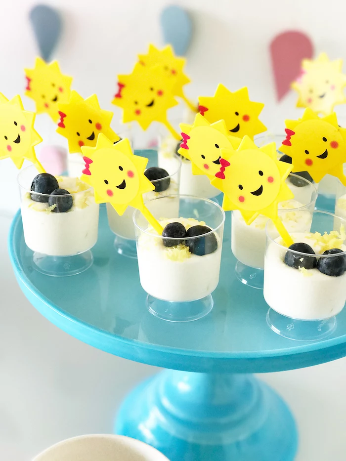 yoghurt with lemon zest, blueberries on top, sun cake toppers, on blue cake stand, baby shower themes for girls