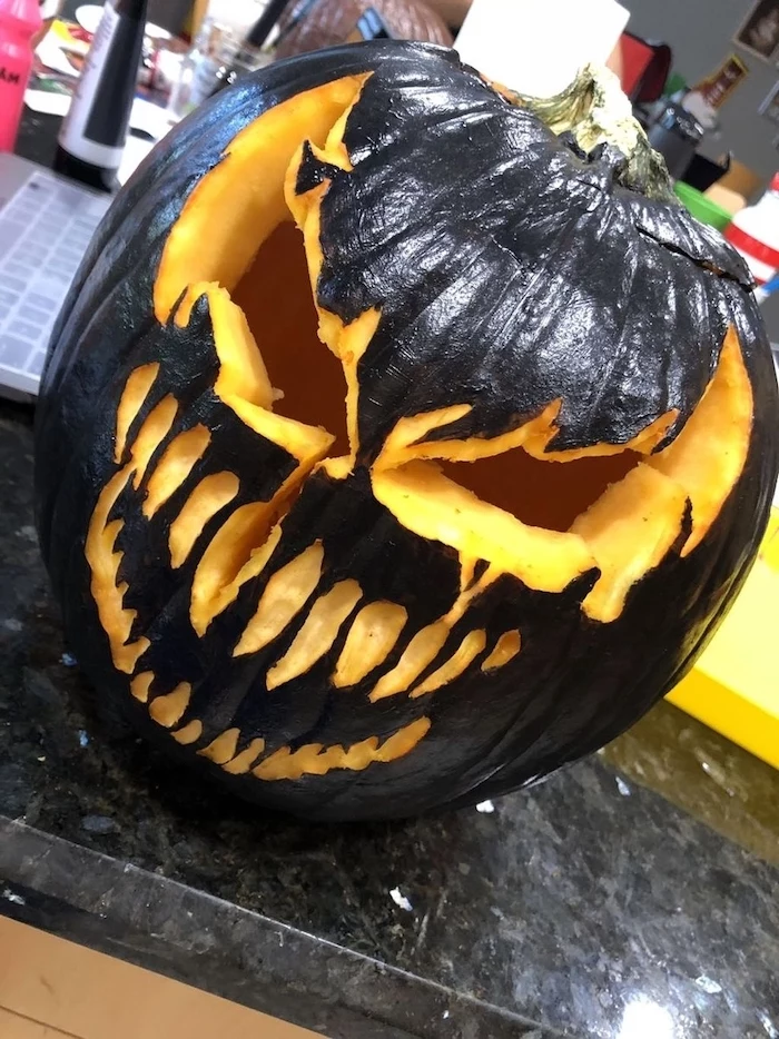 large pumpkin, painted in black, venom movie inspired, funny pumpkin carving, granite countertop