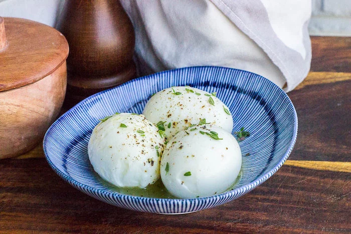 three boiled eggs, with thyme and butter, in a blue and white bowl, keto breakfast recipes, wooden table